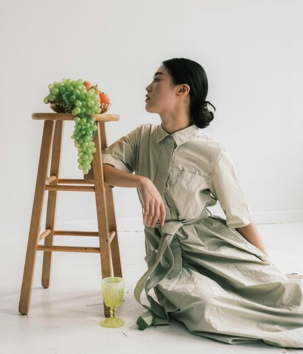 free-photo-of-woman-sitting-on-ground-in-light-shirt-dress-near-stool-with-grapes